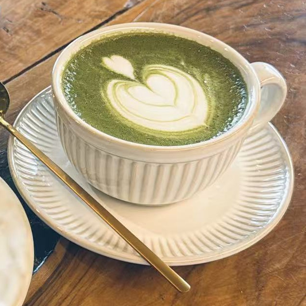 Matcha latte caldo di FYSA con latte art, su un tavolo di legno