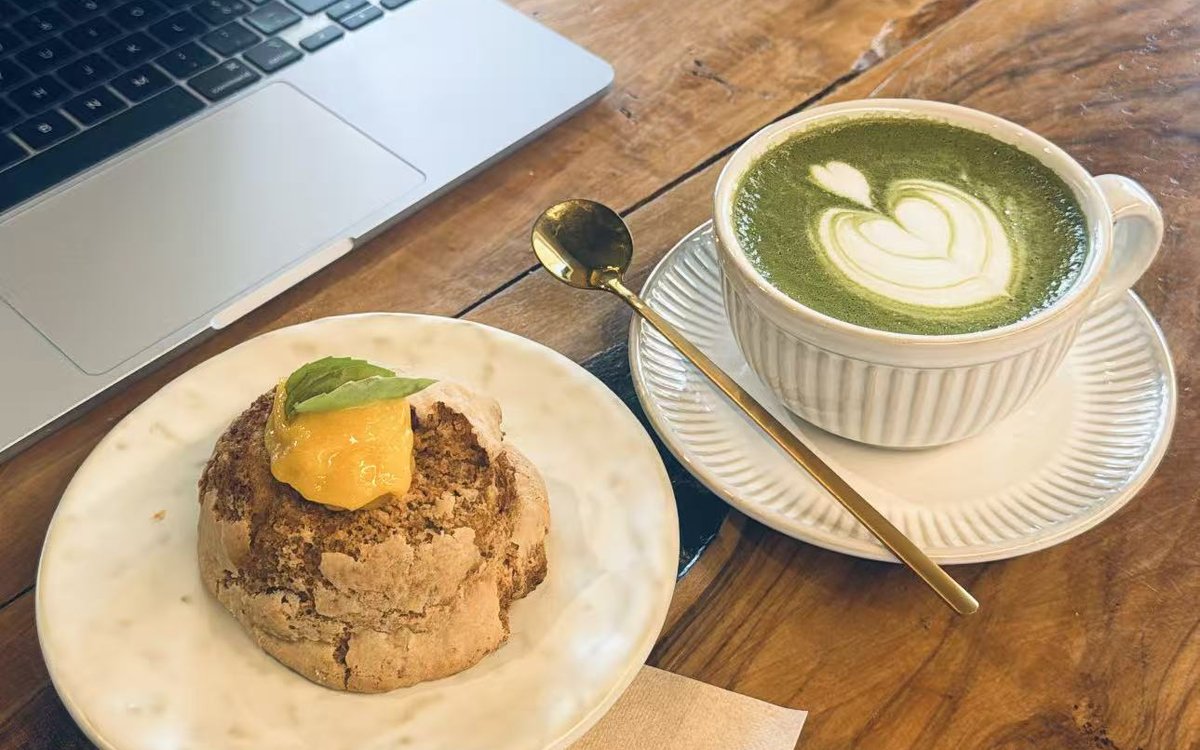 Matcha latte, a pastry and a laptop on a wooden table at FYSA — working from a café in Rome